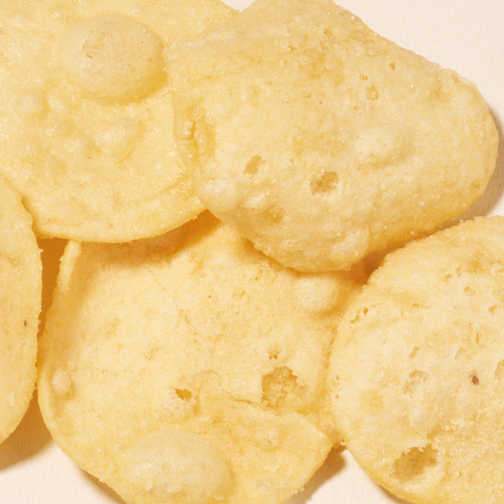 Close-up of several round, light yellow papad chips with a bubbly, crispy texture—perfect for enjoying as part of your Bokksu Snack Box: Seasons of Japan or adding to your Japanese snacks collection.